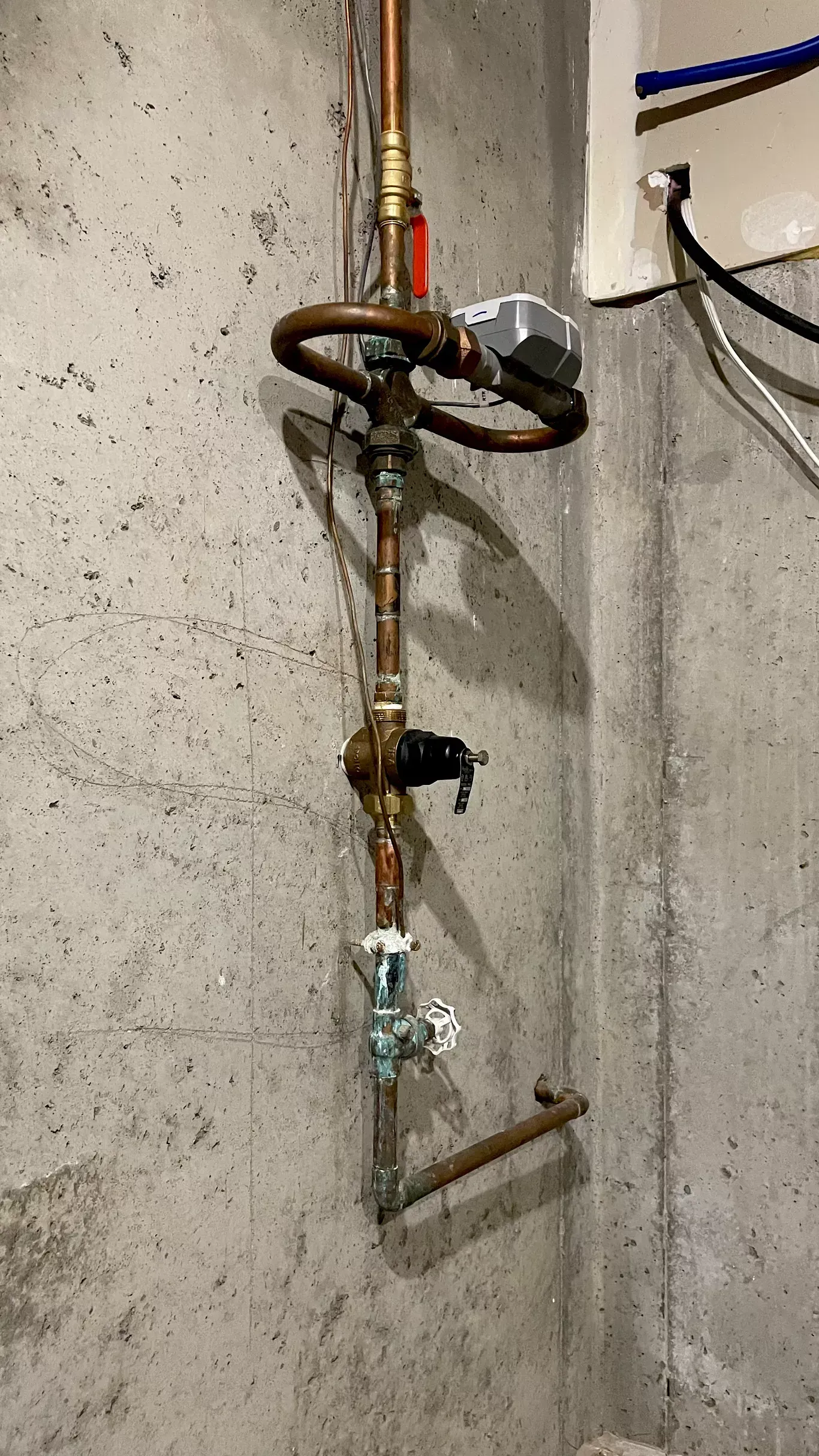 A close up of a copper pipe on a concrete wall.