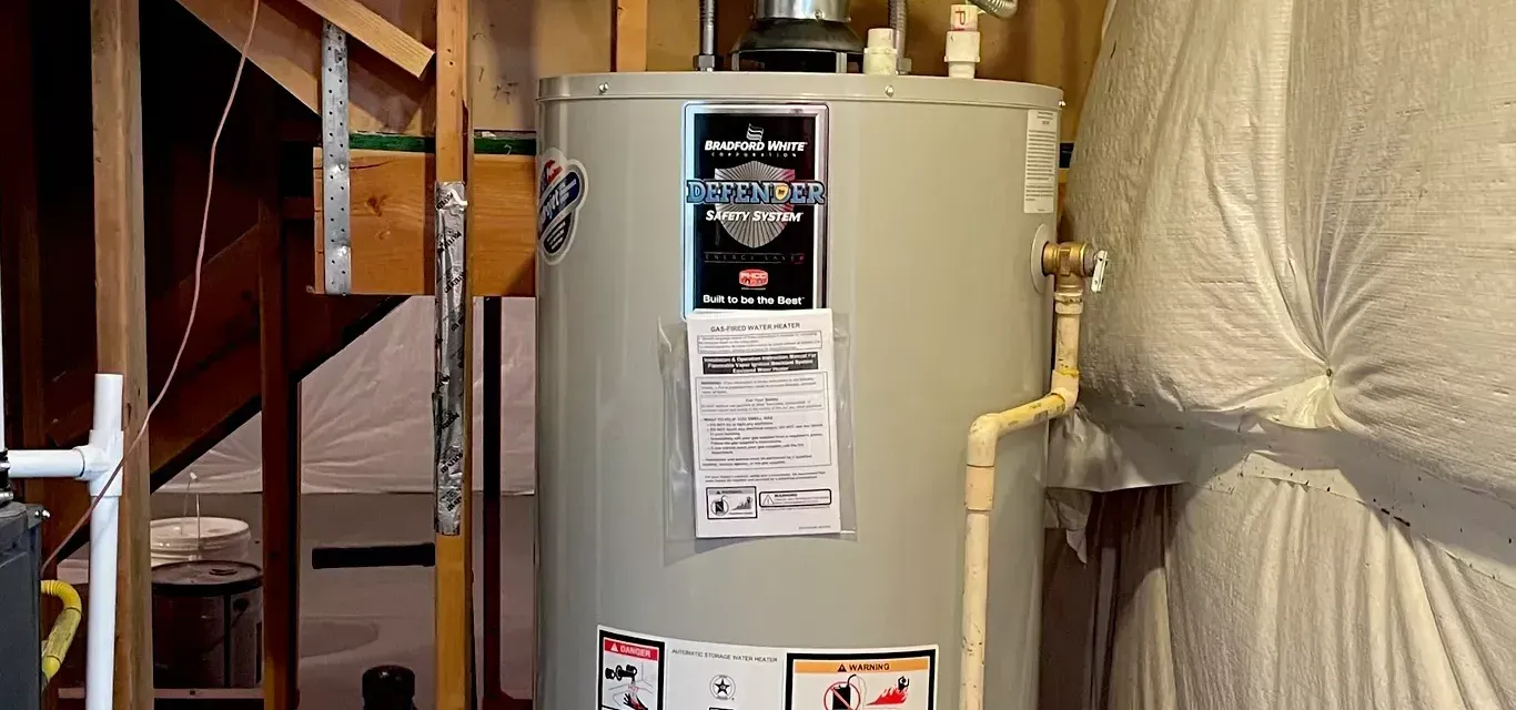 A water heater is sitting in a basement next to a staircase.