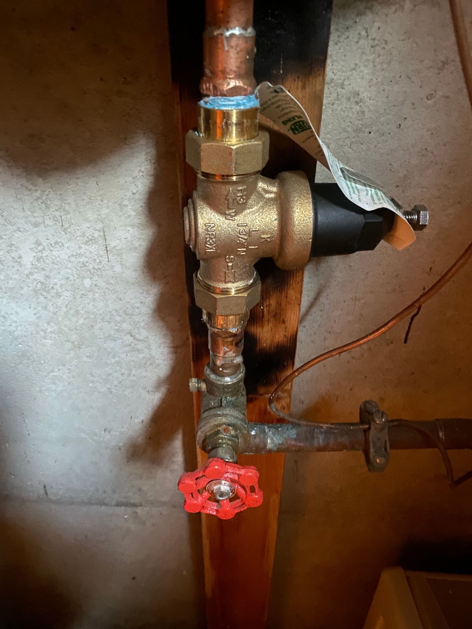 A close up of a copper pipe with a red valve attached to it.