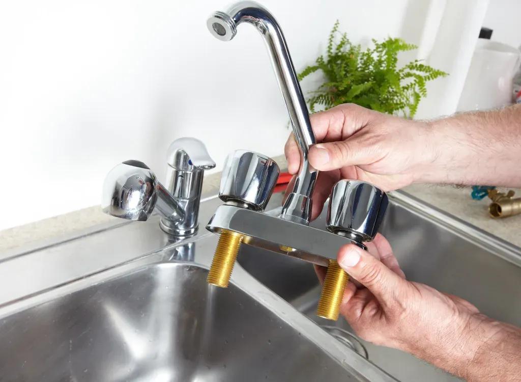 A person is fixing a faucet in a kitchen sink.