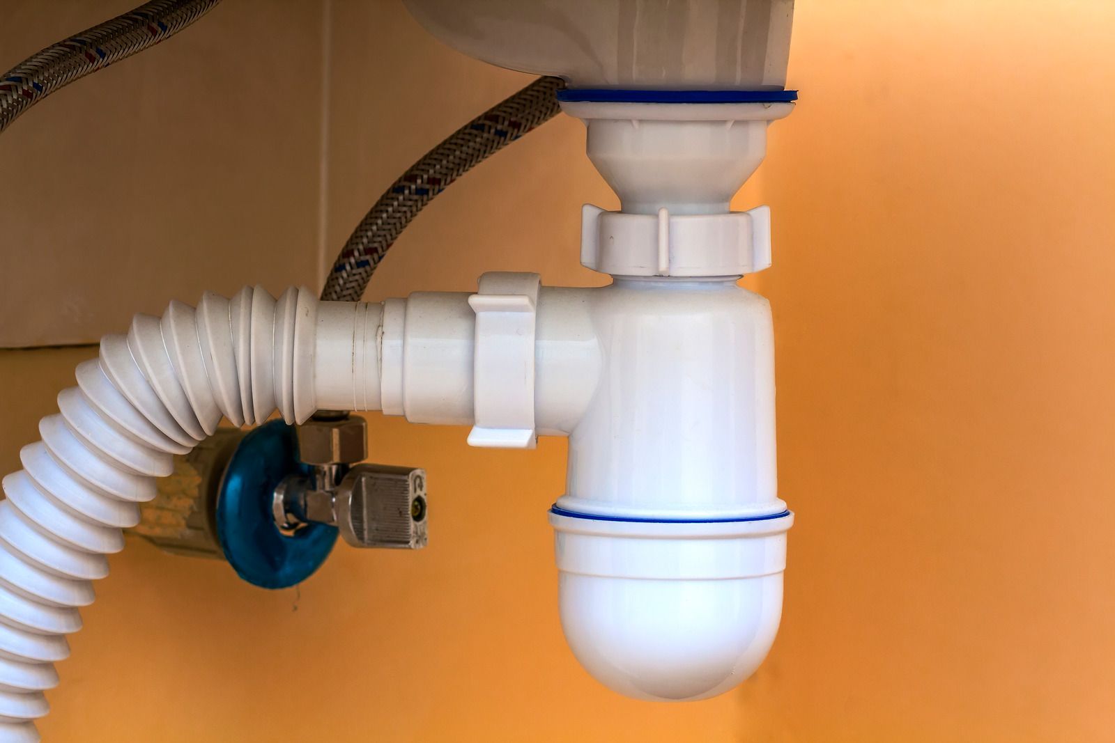 A close up of a sink drain with a hose attached to it.