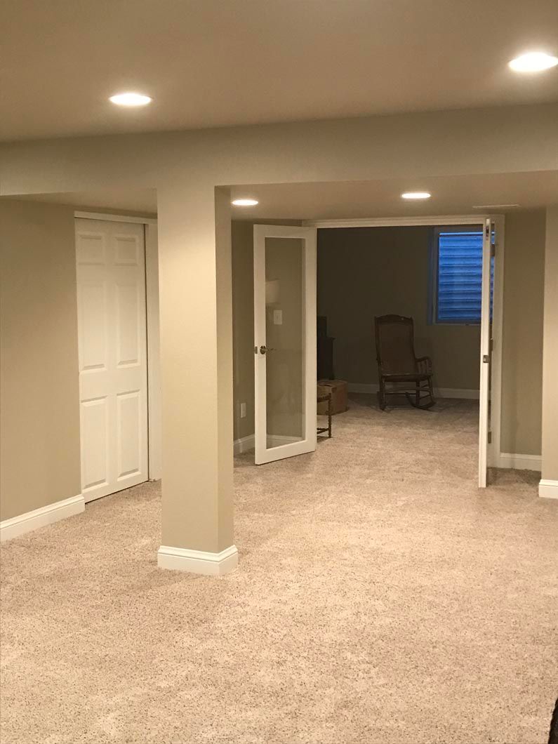 A basement with a carpeted floor and a rocking chair.