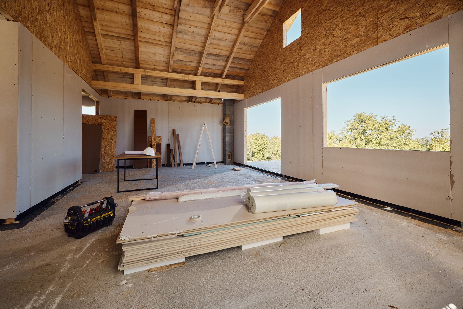 A room under construction with a stack of wooden boards on the floor.