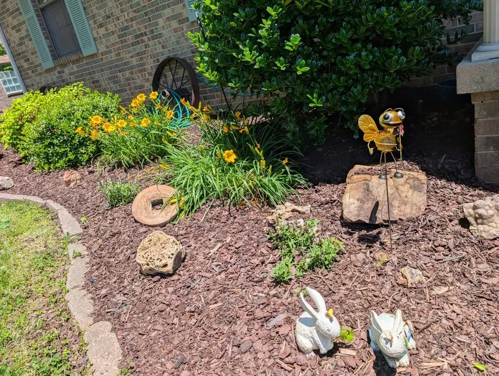 Flowerbed with yellow flowers, garden ornaments, and a metal squirrel statue.