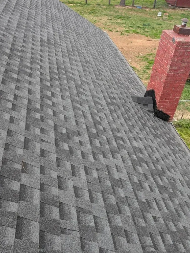 Gray asphalt shingle roof with a red brick chimney.