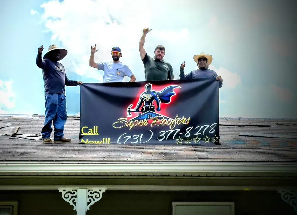 Four people holding a banner on a roof; banner says 