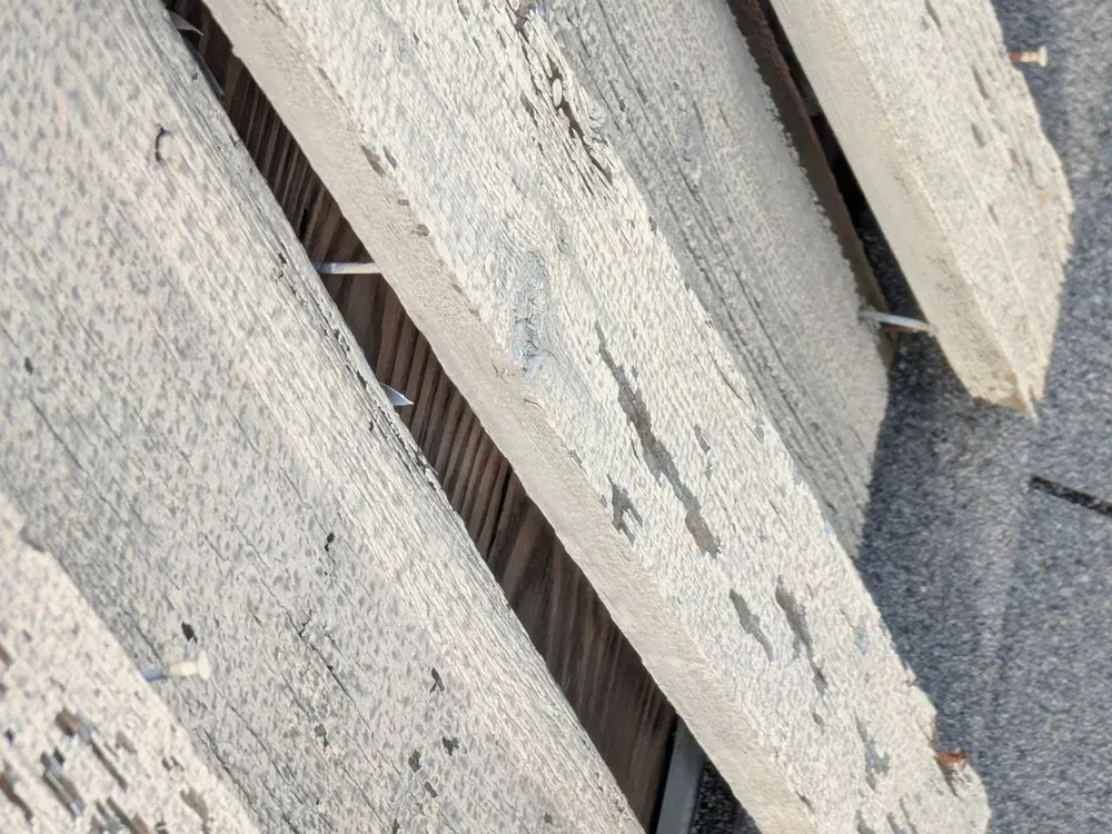Weathered wooden planks, painted white, on a dark roof.