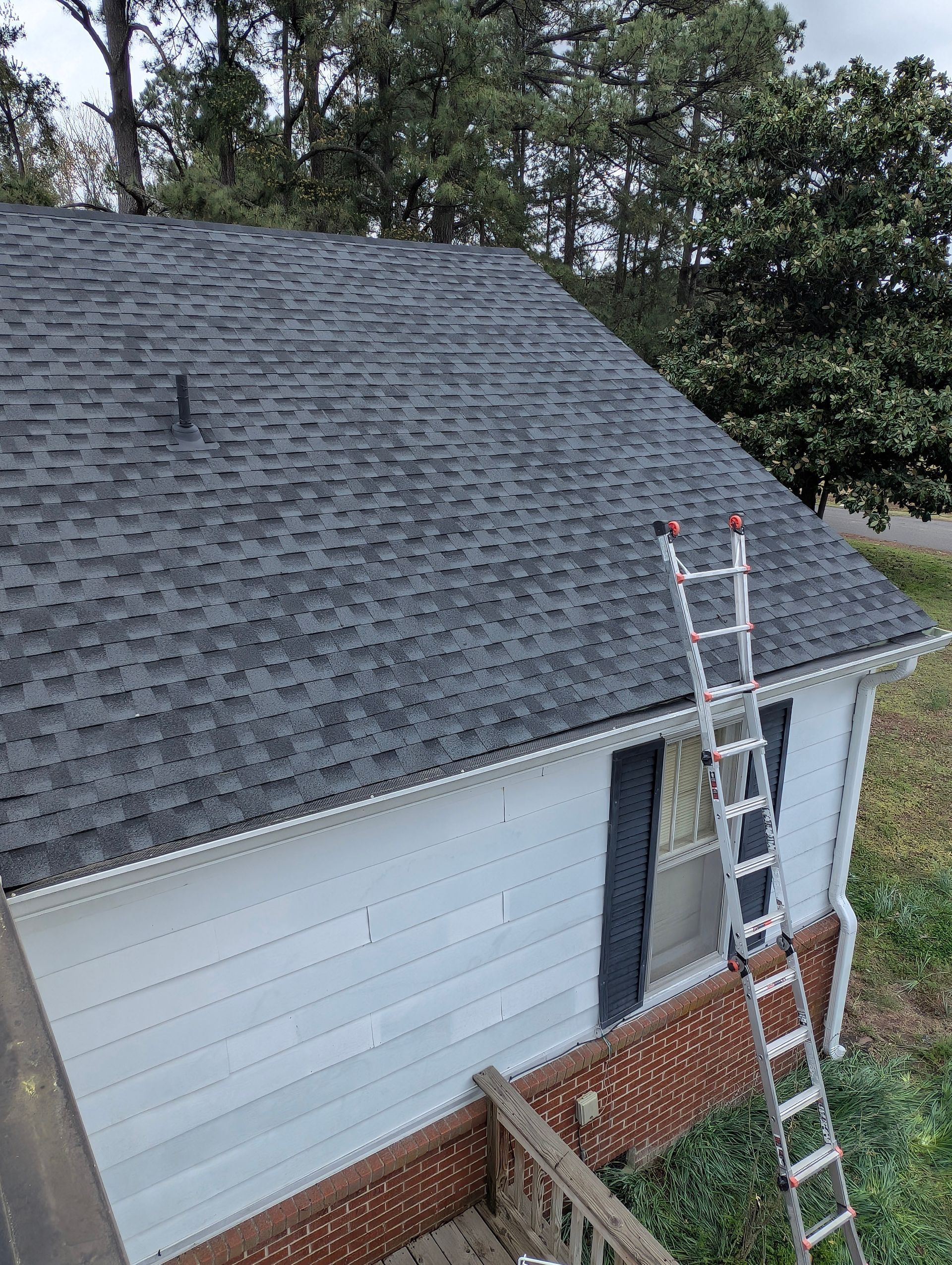 A-frame building with a dark shingle roof, white siding, and a ladder leaning against it.