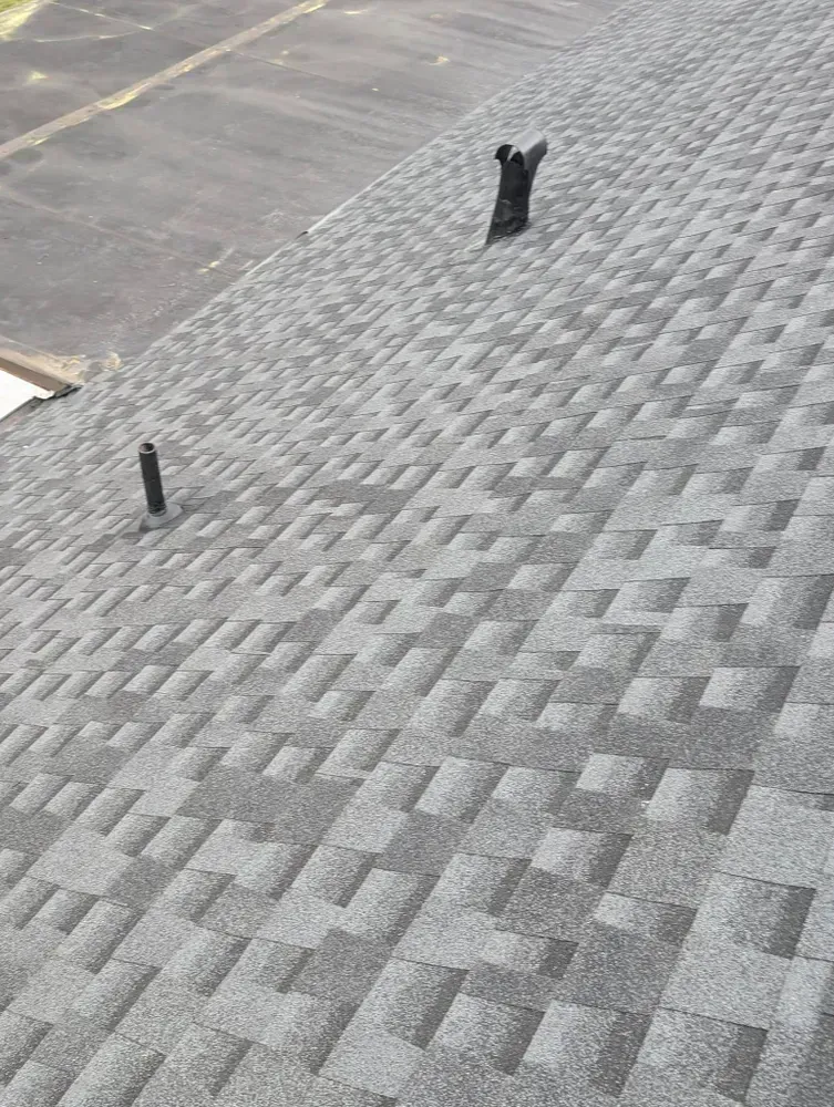 Gray asphalt shingle roof with two vents, angled view.