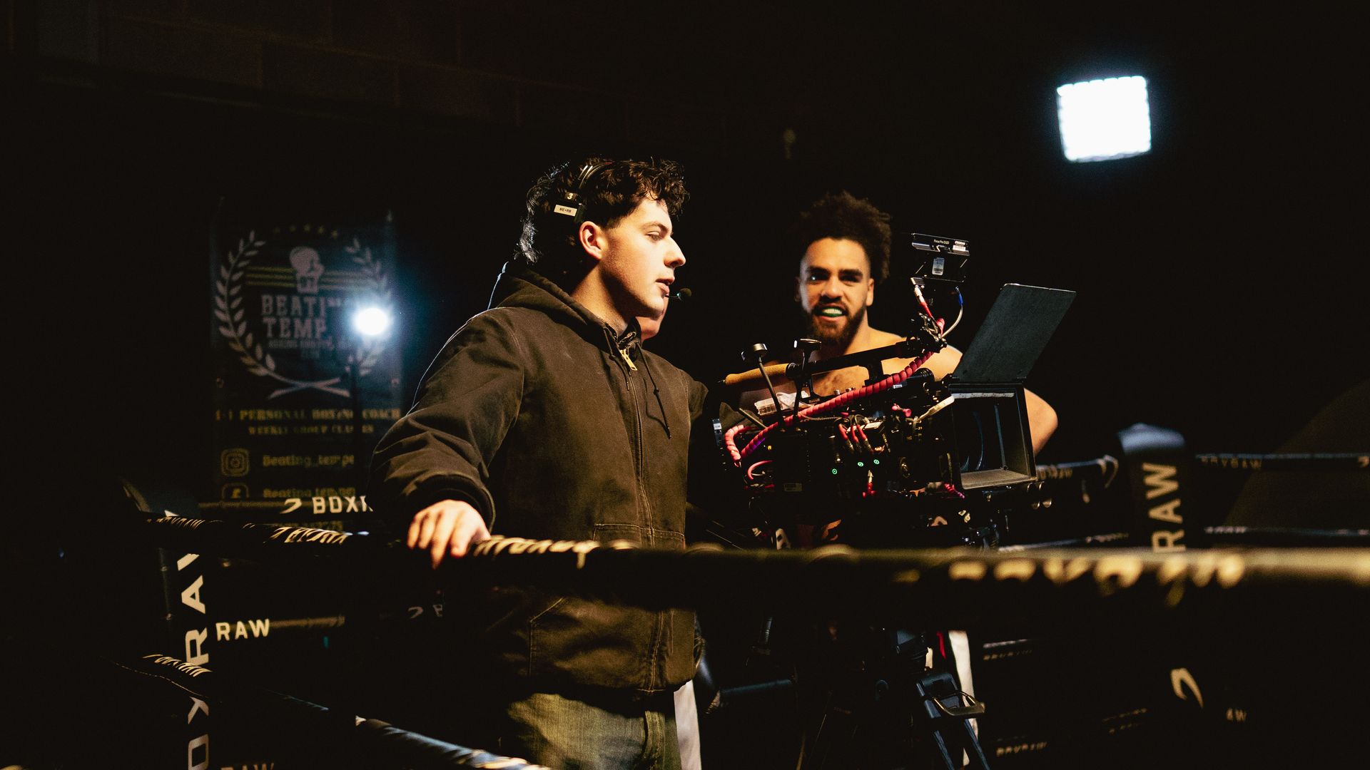 Two men are standing next to each other in a dark room playing instruments.