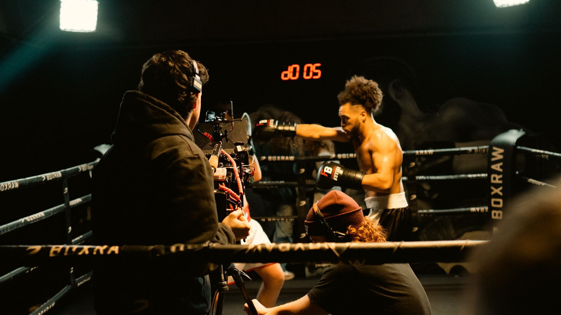 A man is boxing in a boxing ring with a timer on the wall.