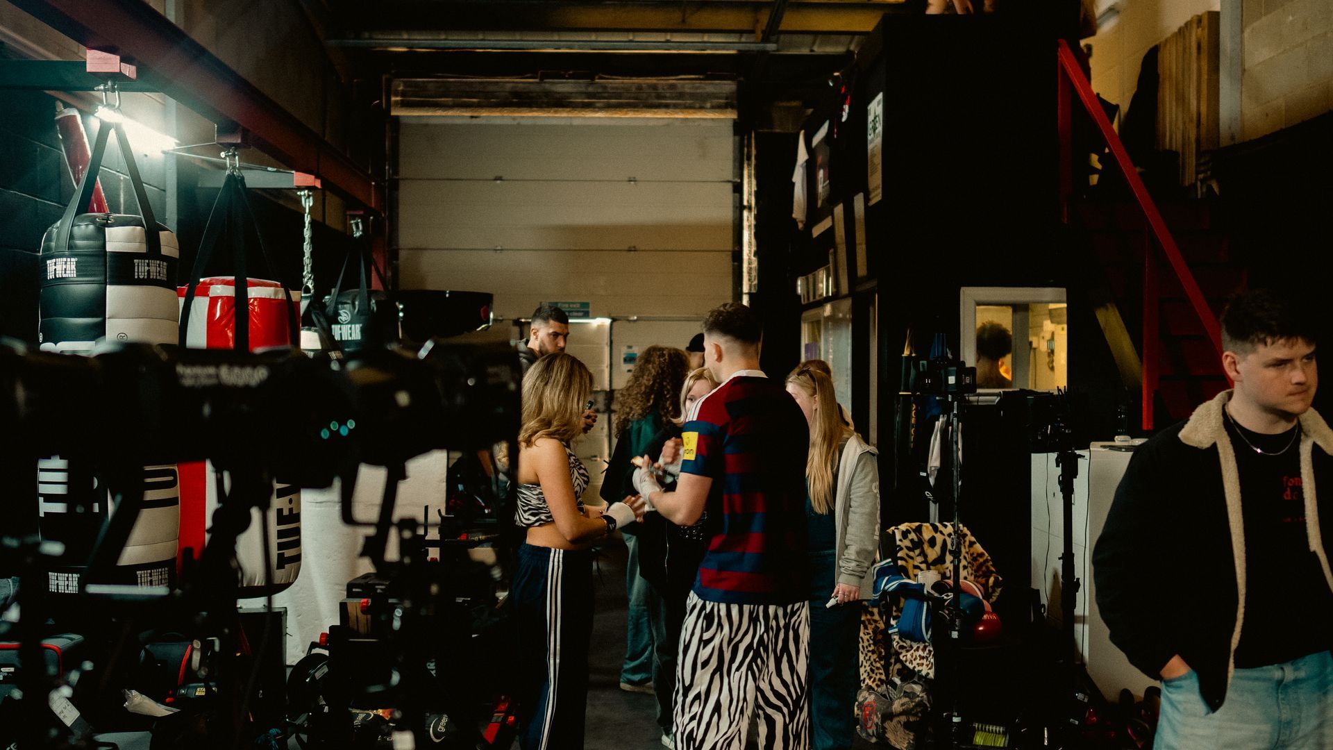 A group of people are standing in a gym talking to each other.