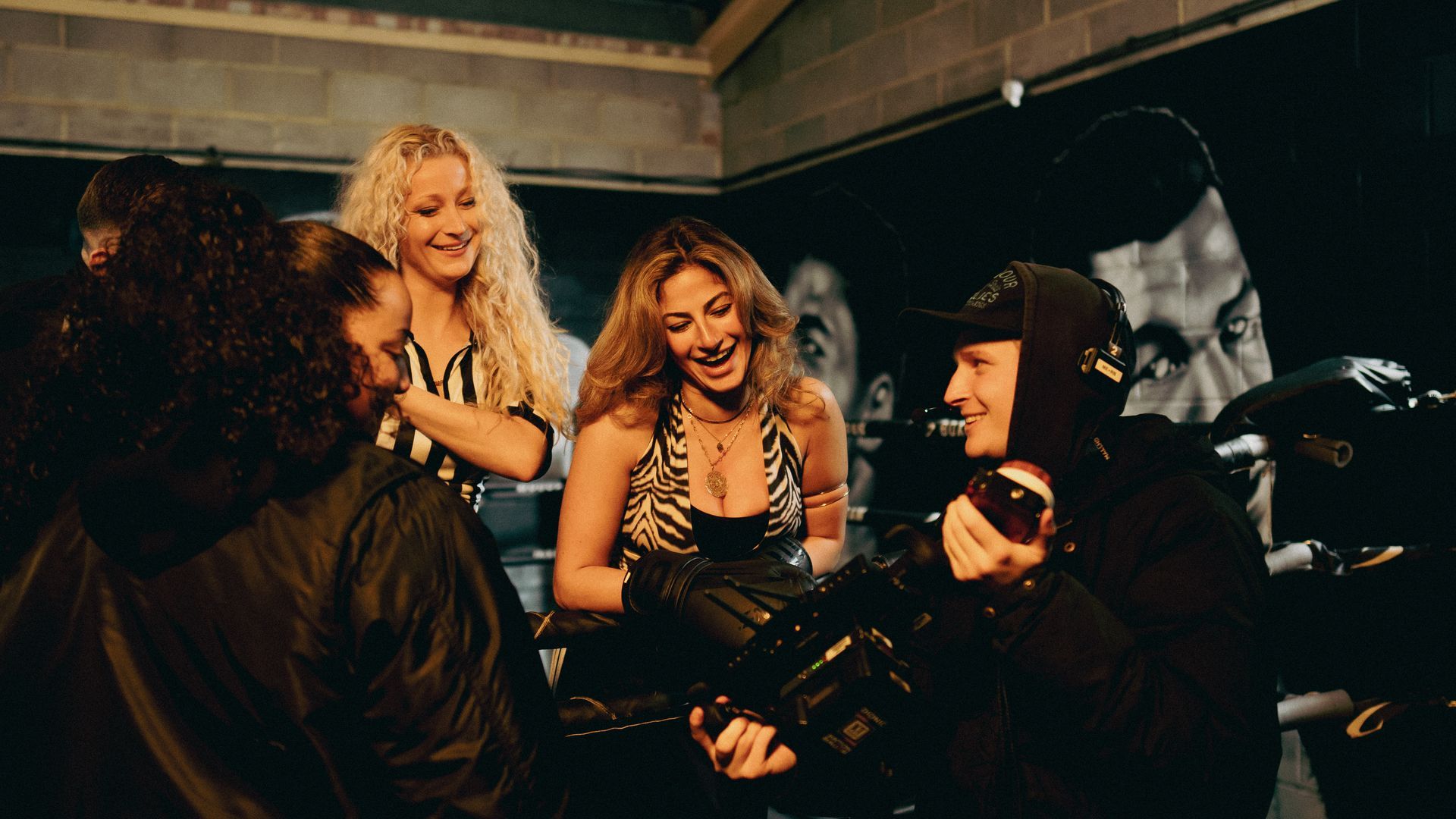 A group of people are standing around a man holding a camera.