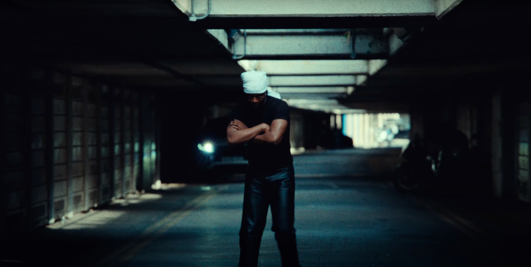 A man is standing in a dark tunnel with his arms crossed.