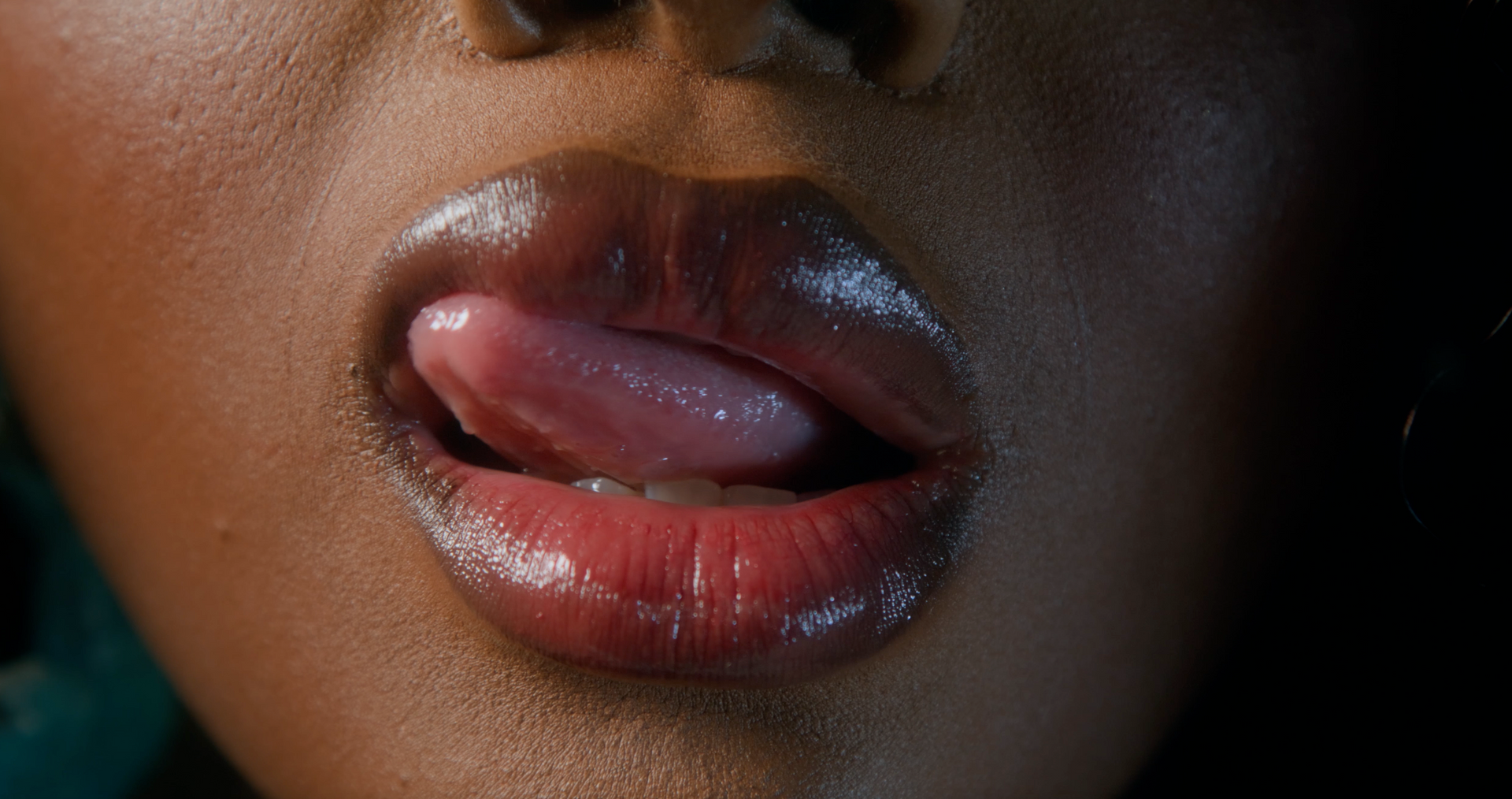 A close up of a woman 's lips sticking out her tongue.
