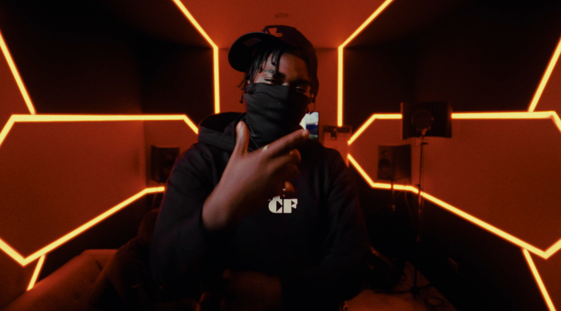 A man wearing a mask and a hat is making a peace sign.