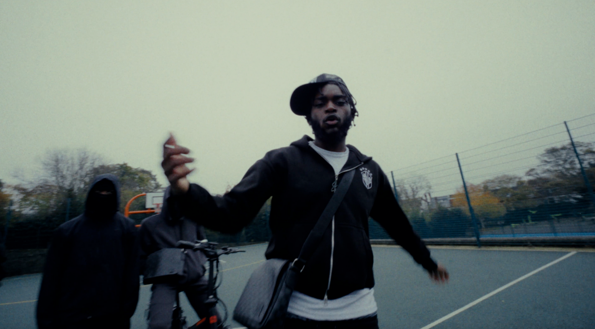 A man in a black jacket is standing on a basketball court.