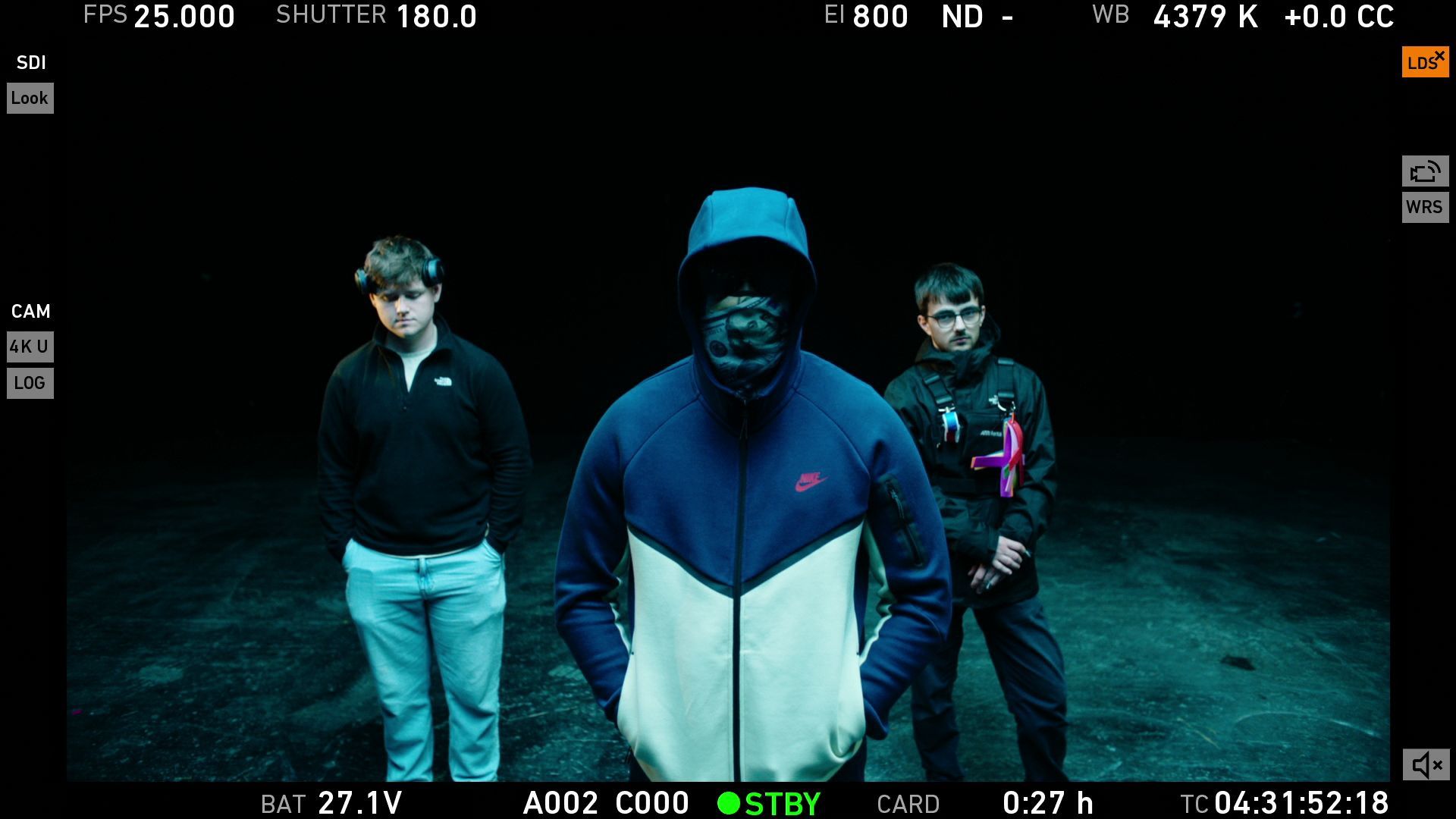 Three men are standing next to each other in a dark room.