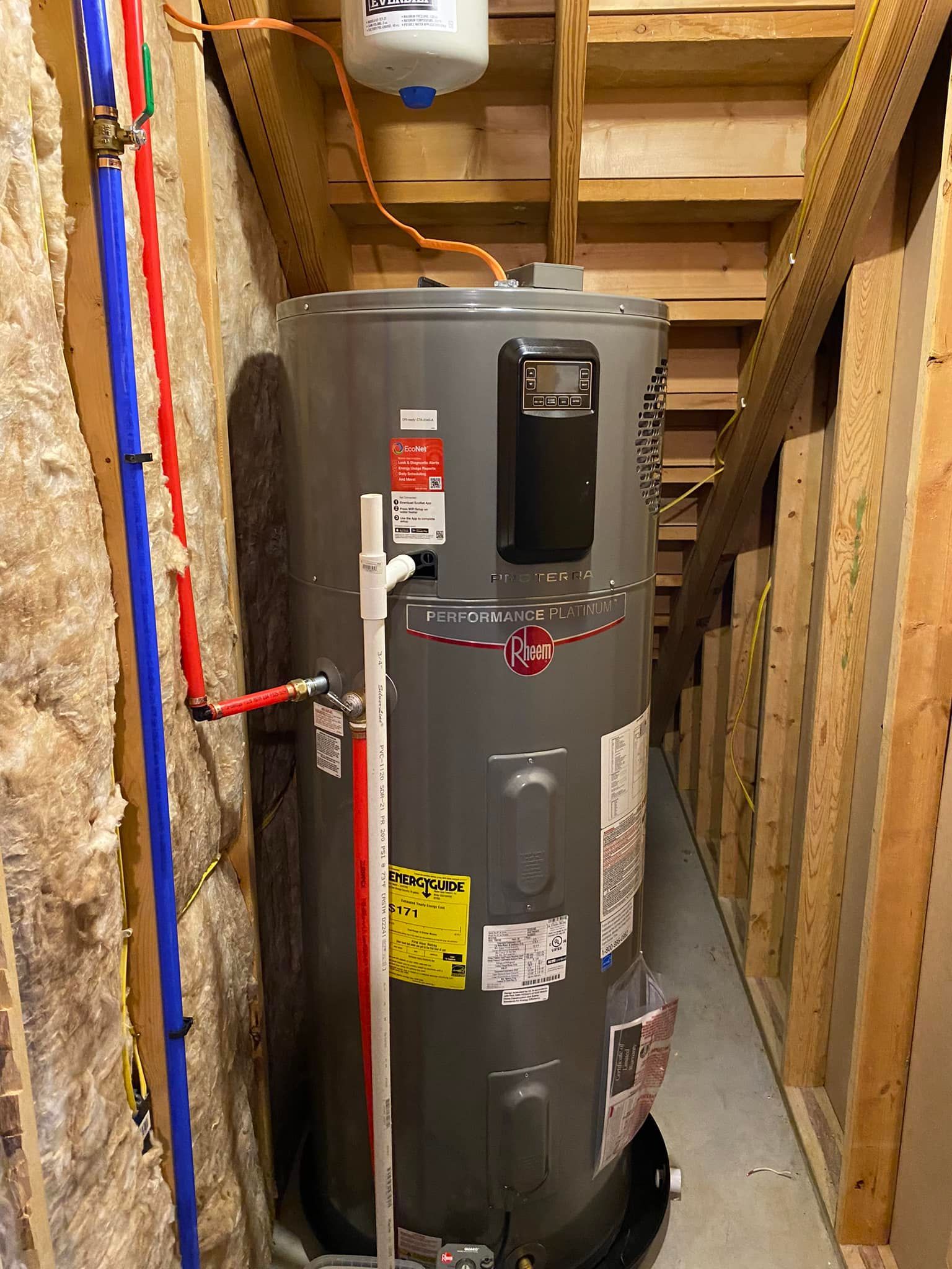 A Water Heater Is Sitting in A Narrow Hallway Next to A Wooden Wall - Bristol, TN - Austin’s Plumbing, LLC