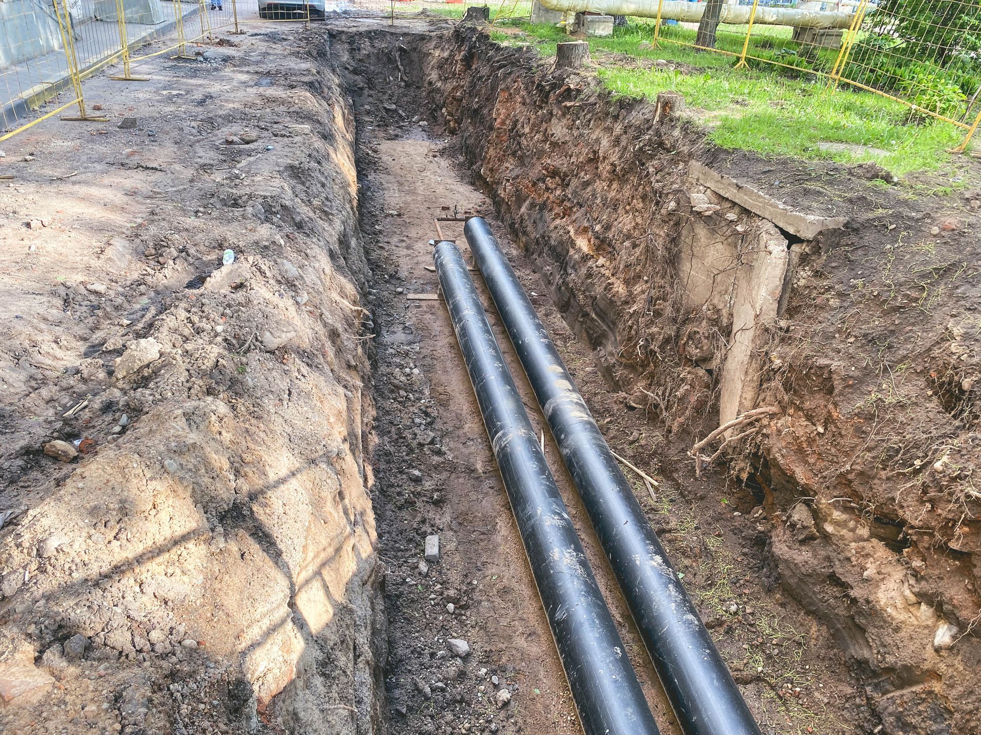 Two Black Pipes Are Laying in The Dirt in A Trench - Bristol, TN - Austin’s Plumbing, LLC