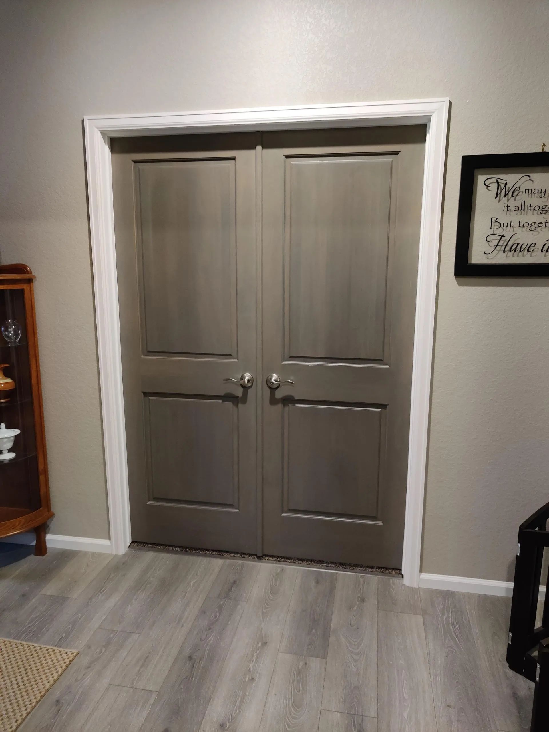 Two gray, paneled doors with white trim, in a gray-walled room with wood flooring.