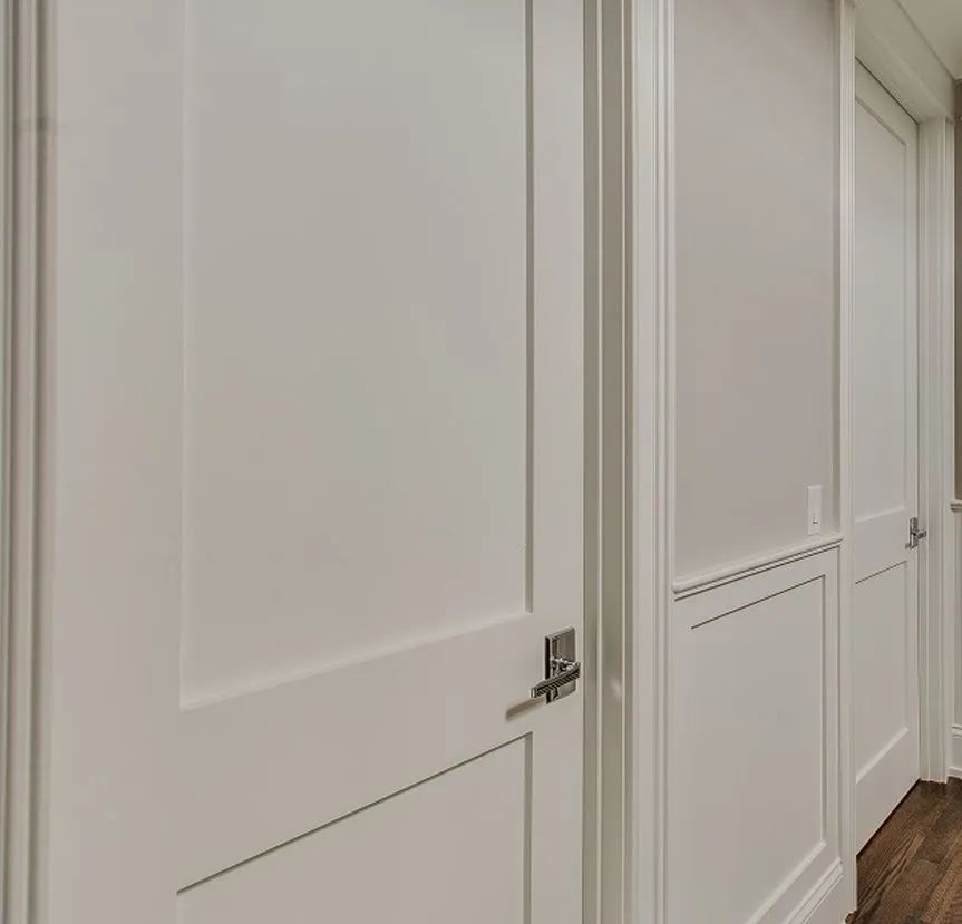 A hallway showing two white interior doors with shaker-style panels and modern brushed metal handles.
