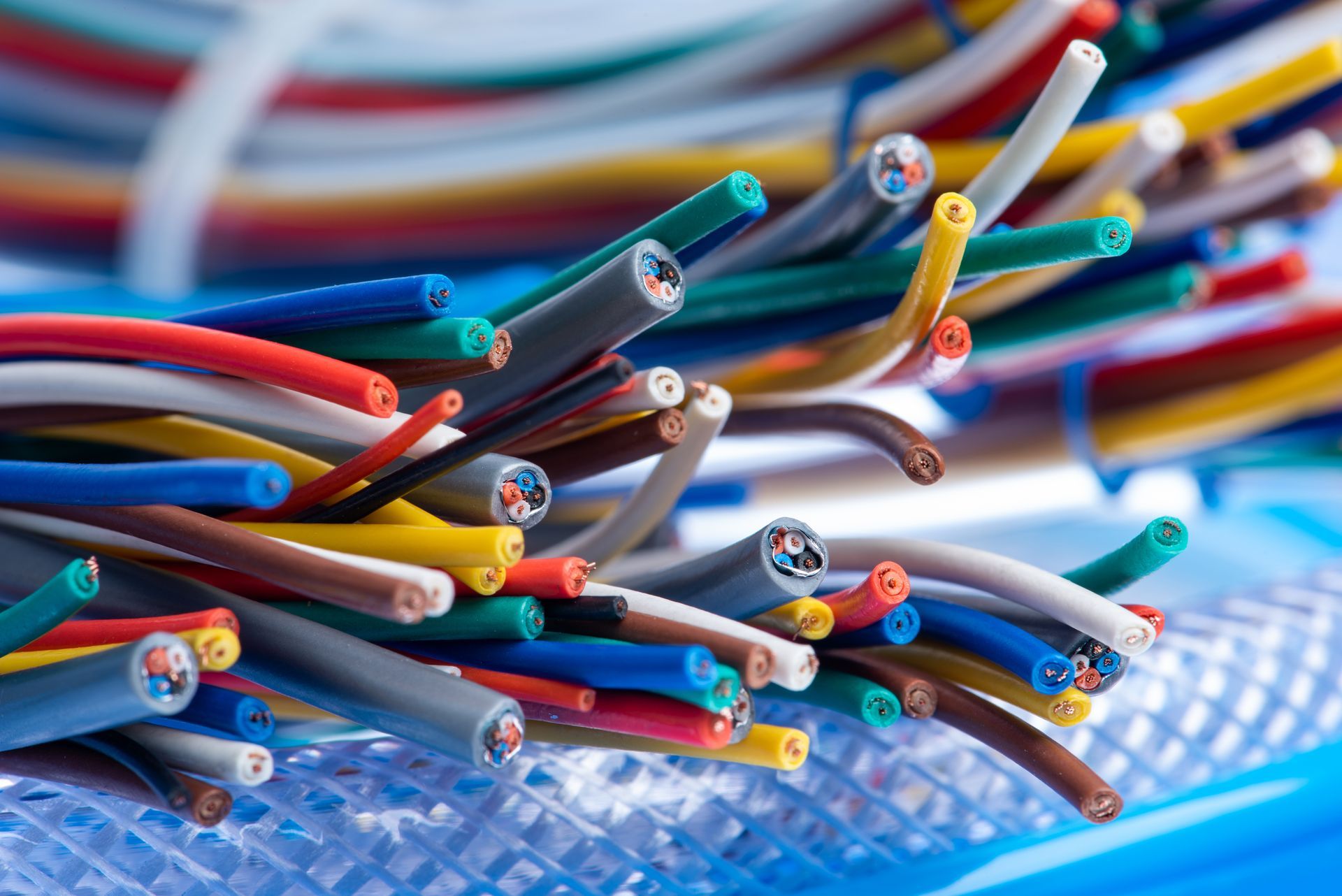 Fascio di fili elettrici multicolori con estremità esposte su una superficie blu