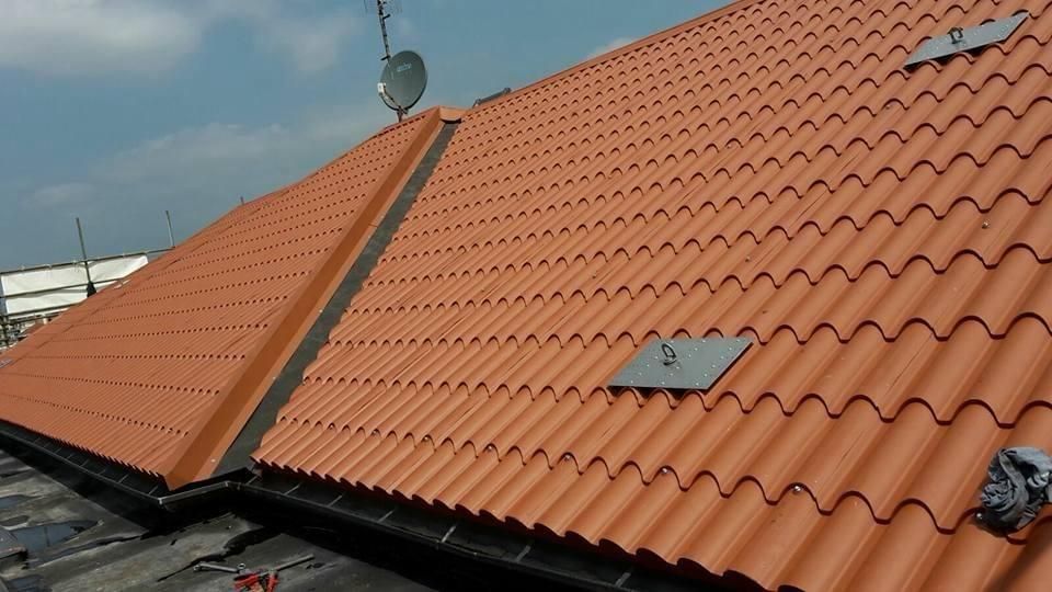 Tetto in tegole di argilla arancioni con pannelli solari e parabola satellitare sotto un cielo limpido.