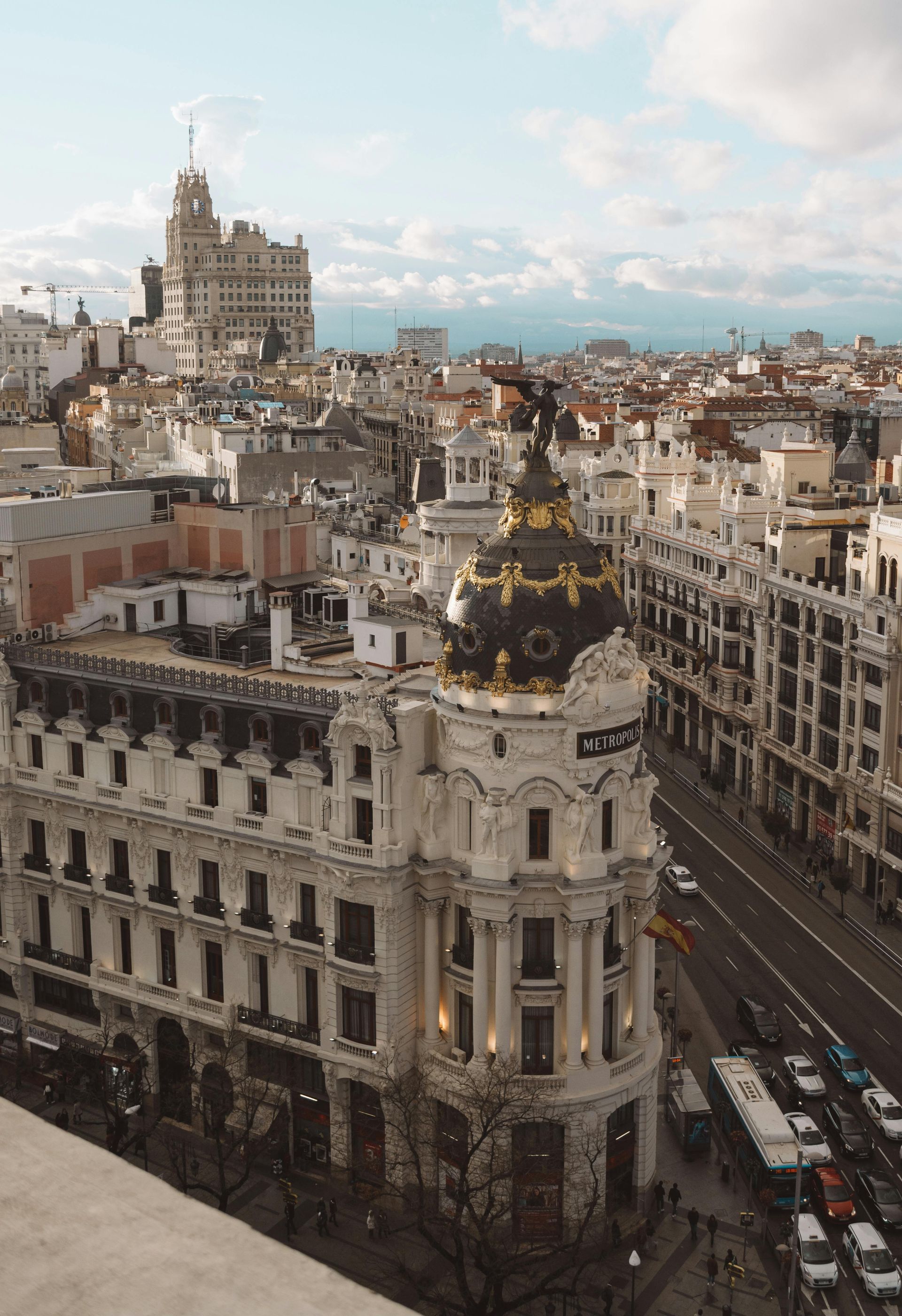 Paisaje urbano de Madrid, España, con edificios ornamentados y una calle concurrida.