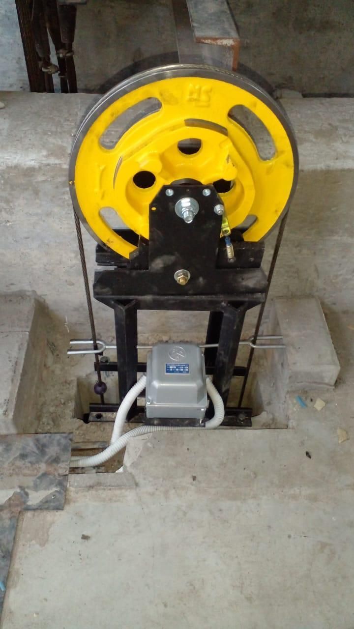 Una polea amarilla está colocada encima de un piso de concreto.