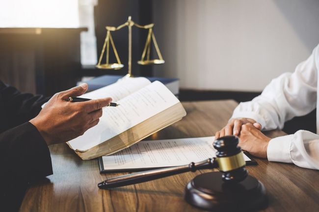 Lawyer and client discussing a case at a desk with scales of justice and gavel