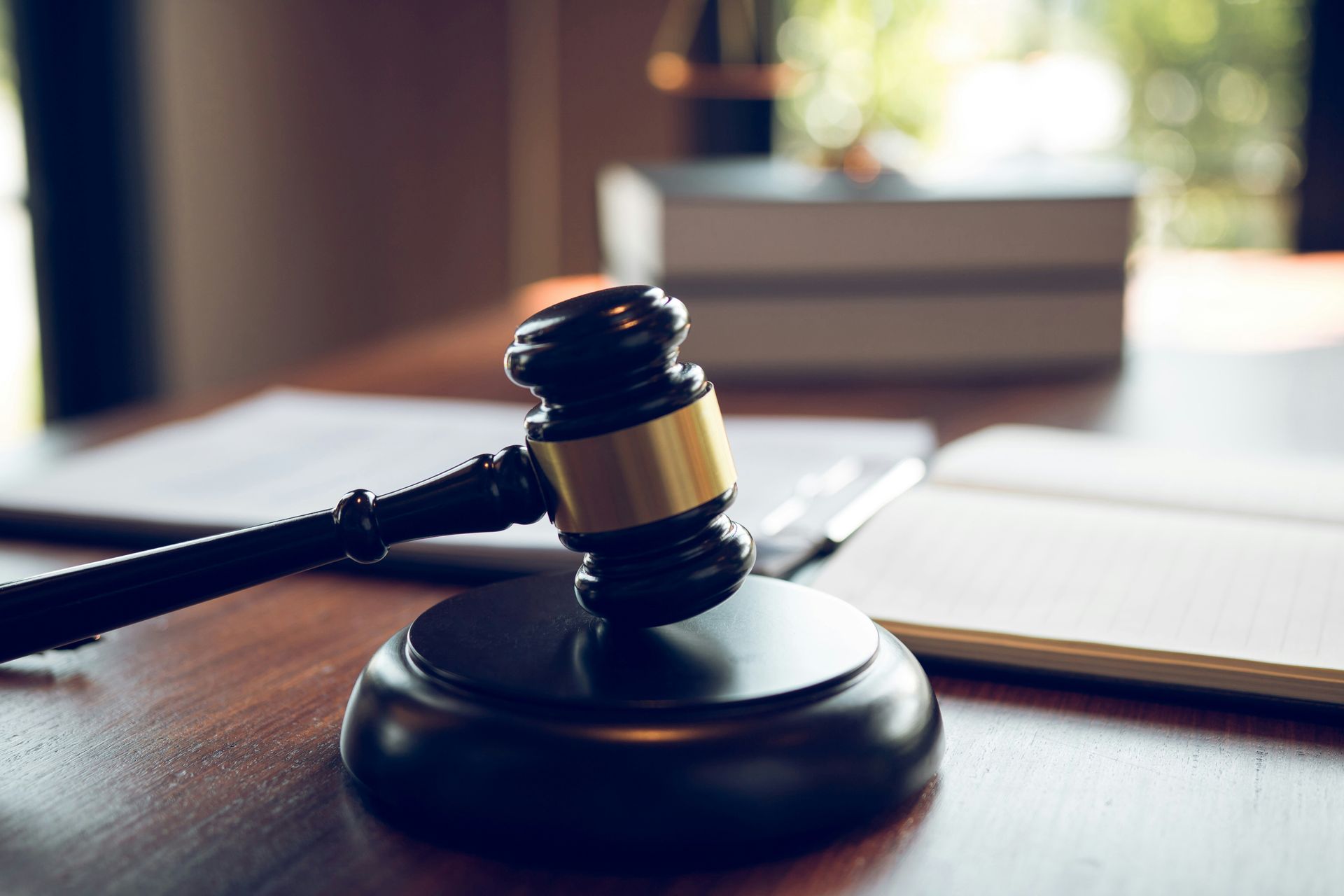 Judge’s gavel on a wooden desk beside an open book in a courtroom setting