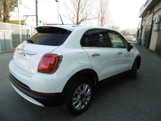 Fiat 500X SUV bianca, parcheggiata all'aperto, vista posteriore. Cerchi argentati, parafanghi neri e vetri oscurati.