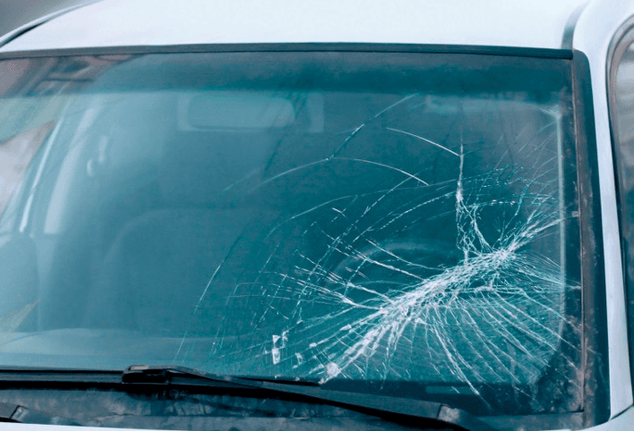 Parabrezza dell'auto rotto, effetto ragnatela. Interni visibili, tergicristalli in basso.