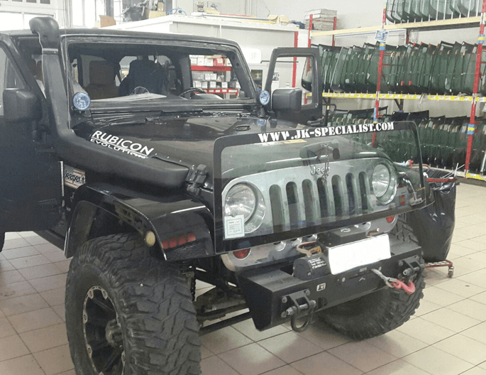 Jeep Rubicon nera con snorkel, frontale modificato, in officina.