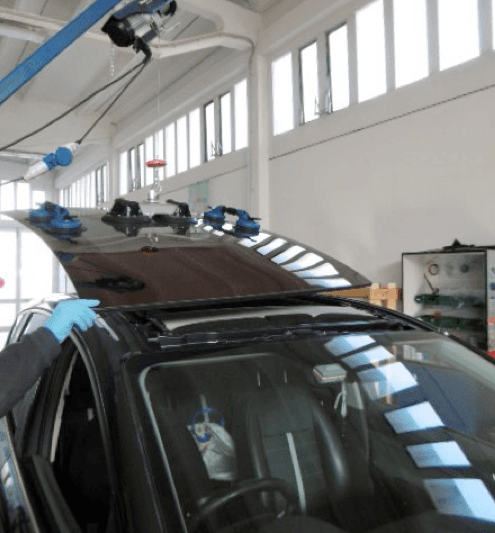 Un meccanico usa le ventose per sollevare il tettuccio apribile di un'auto. In un'officina.