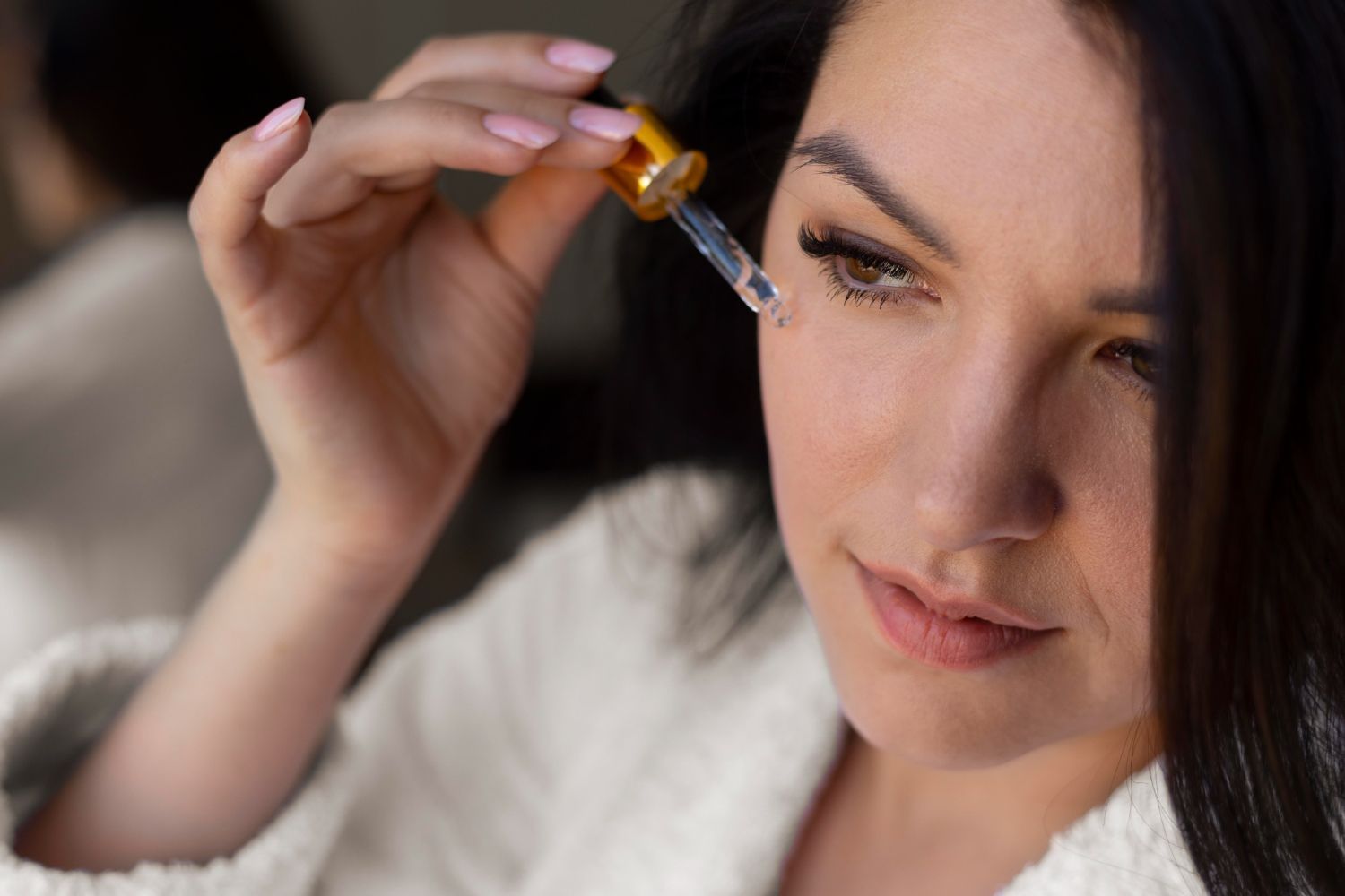 A woman is applying a serum to her face with a pipette.