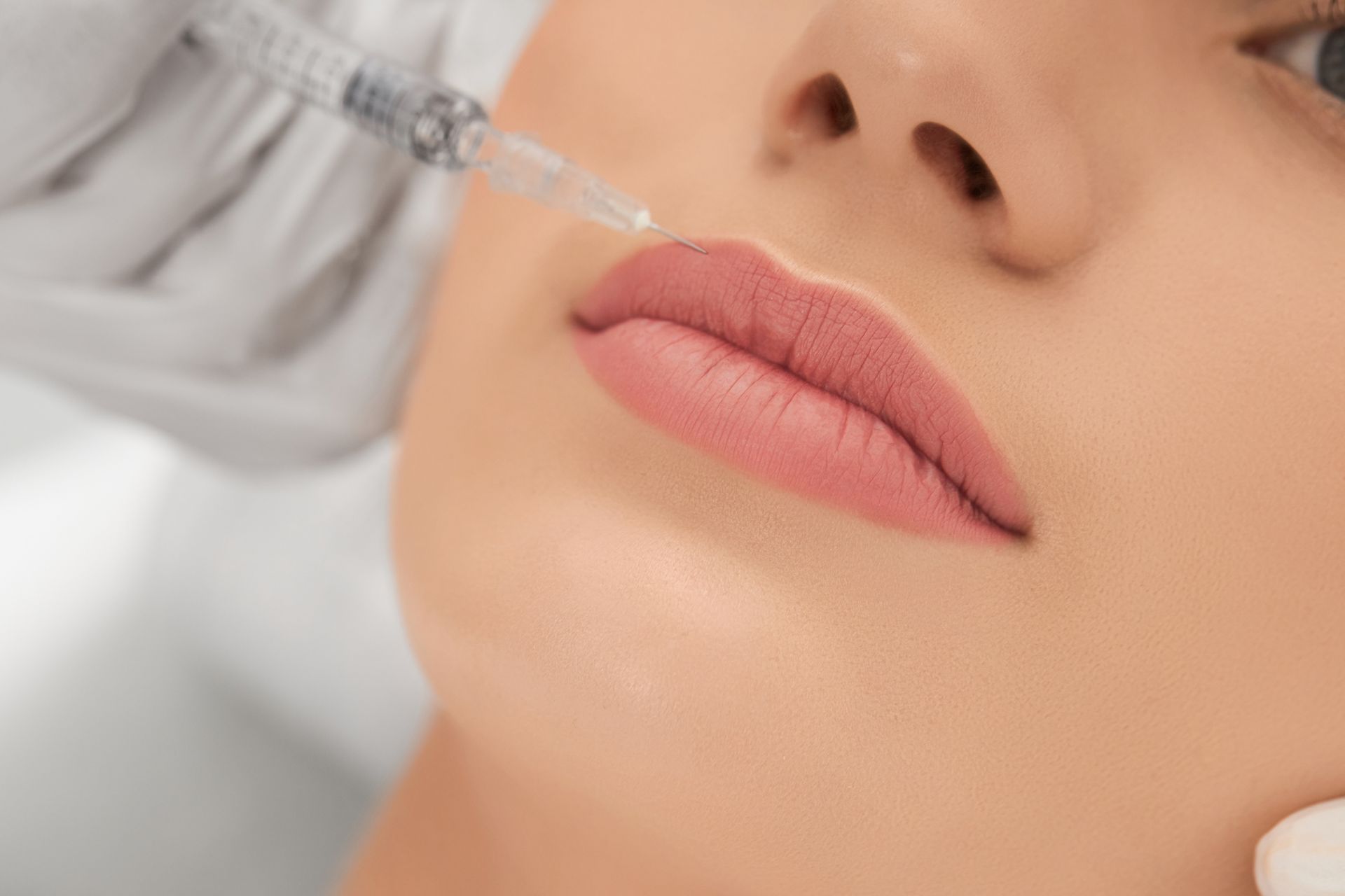 A woman is getting a botox injection in her lips.