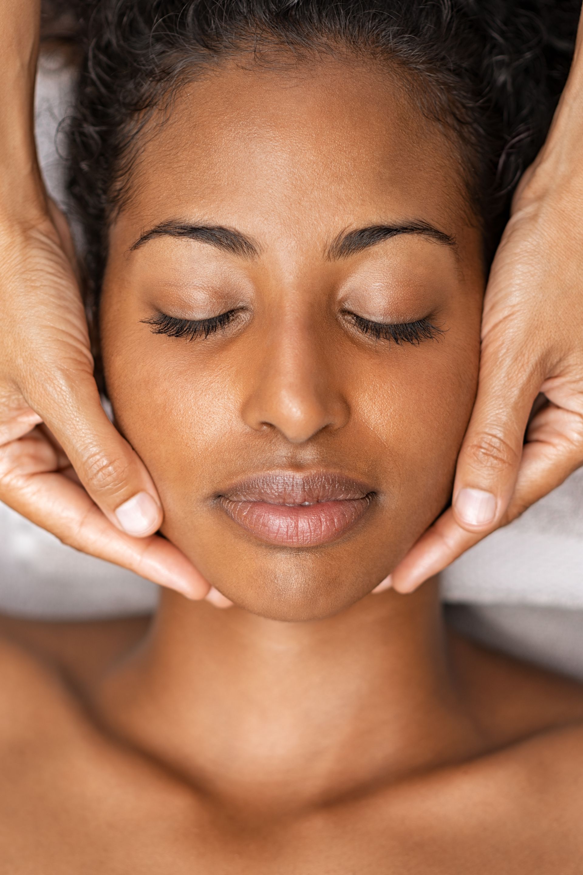 A woman is getting a facial massage at a spa.