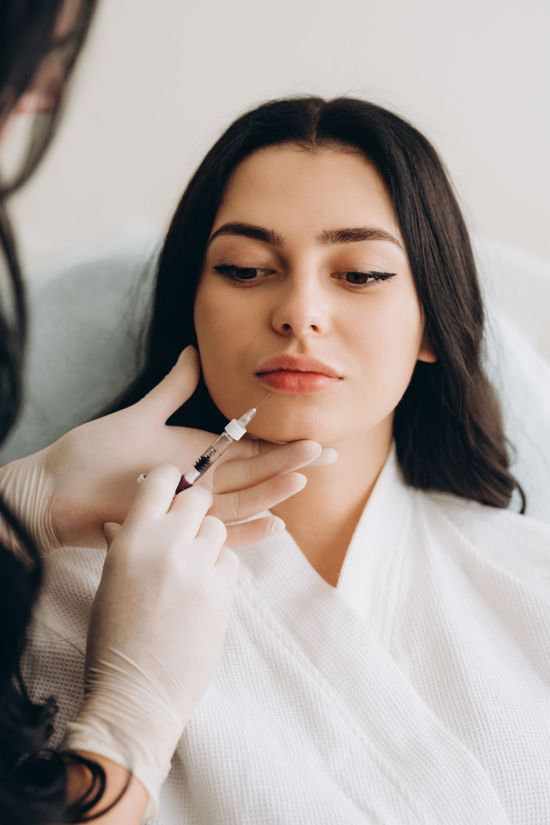 A woman is getting a botox injection in her face.