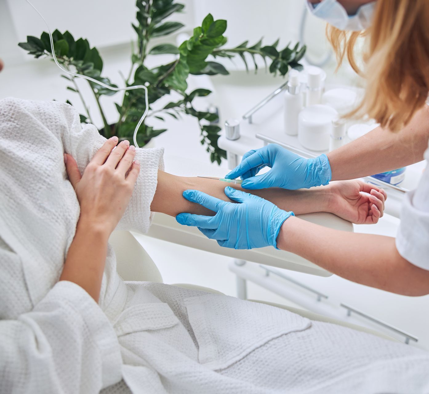 A woman wearing blue gloves is getting an injection in her arm.