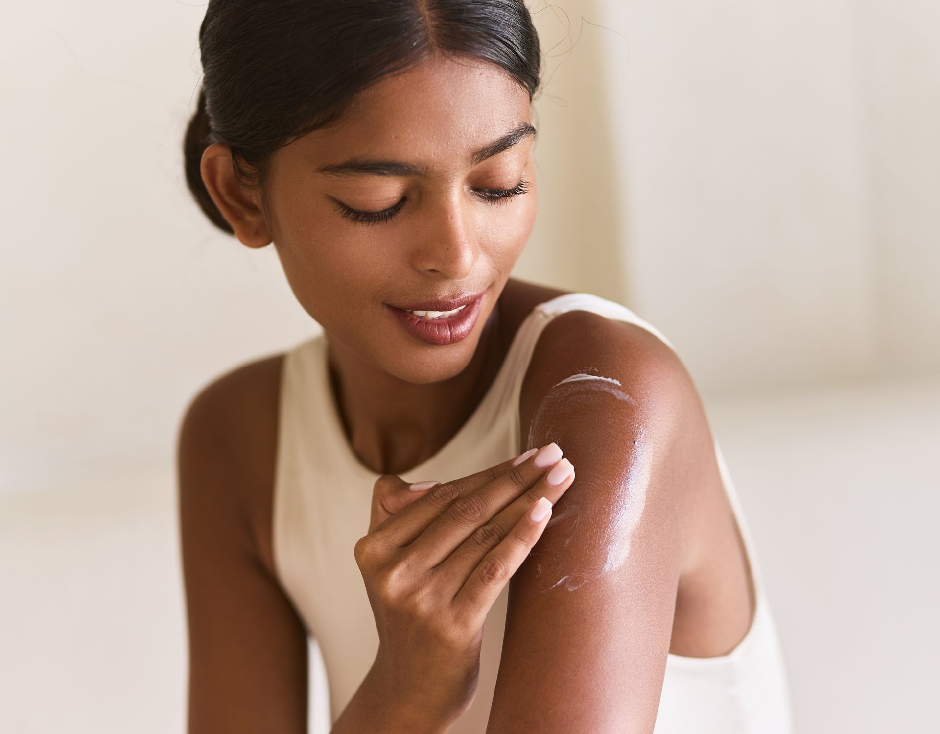 A woman is applying lotion to her arm.