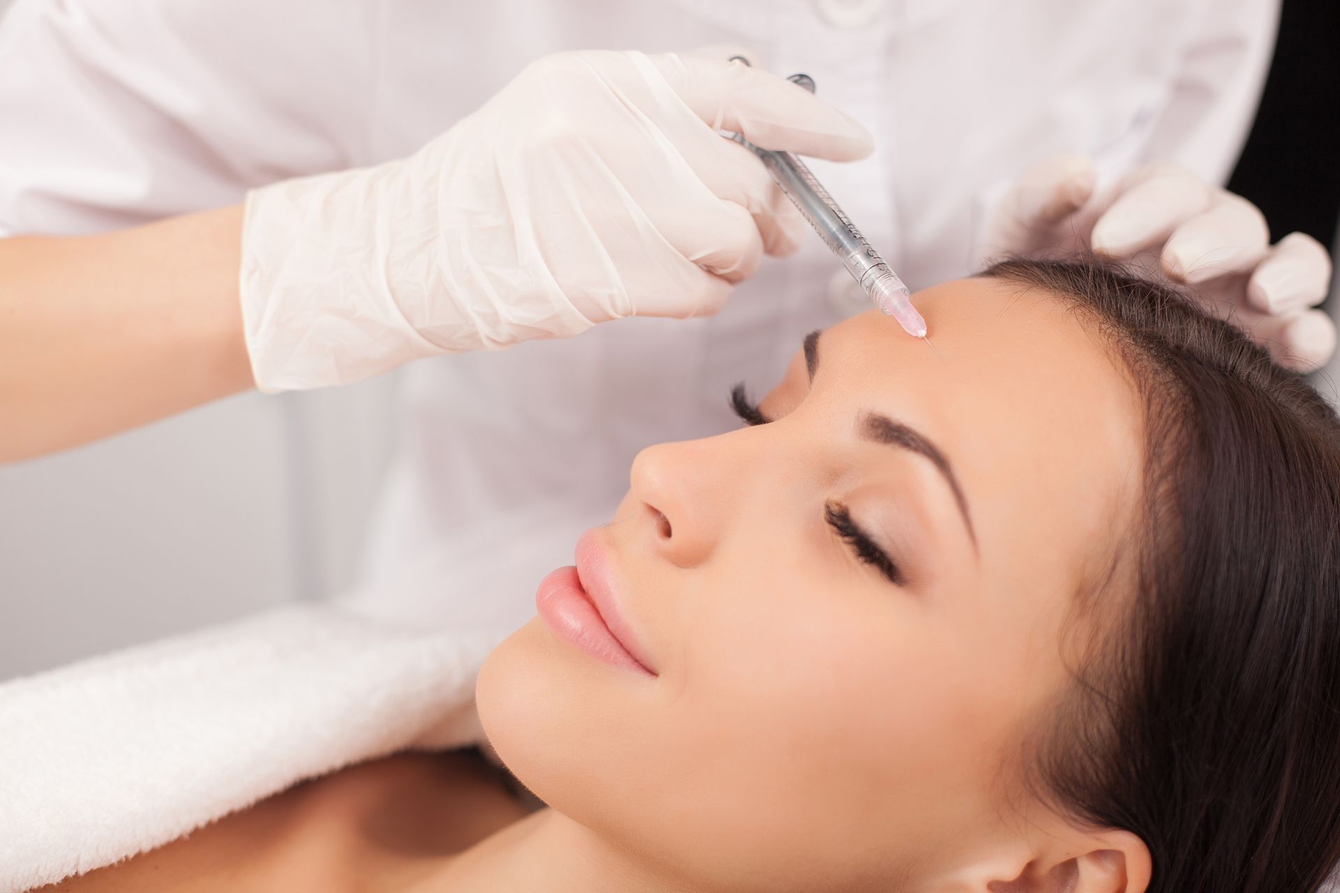 A woman is getting a botox injection on her forehead.