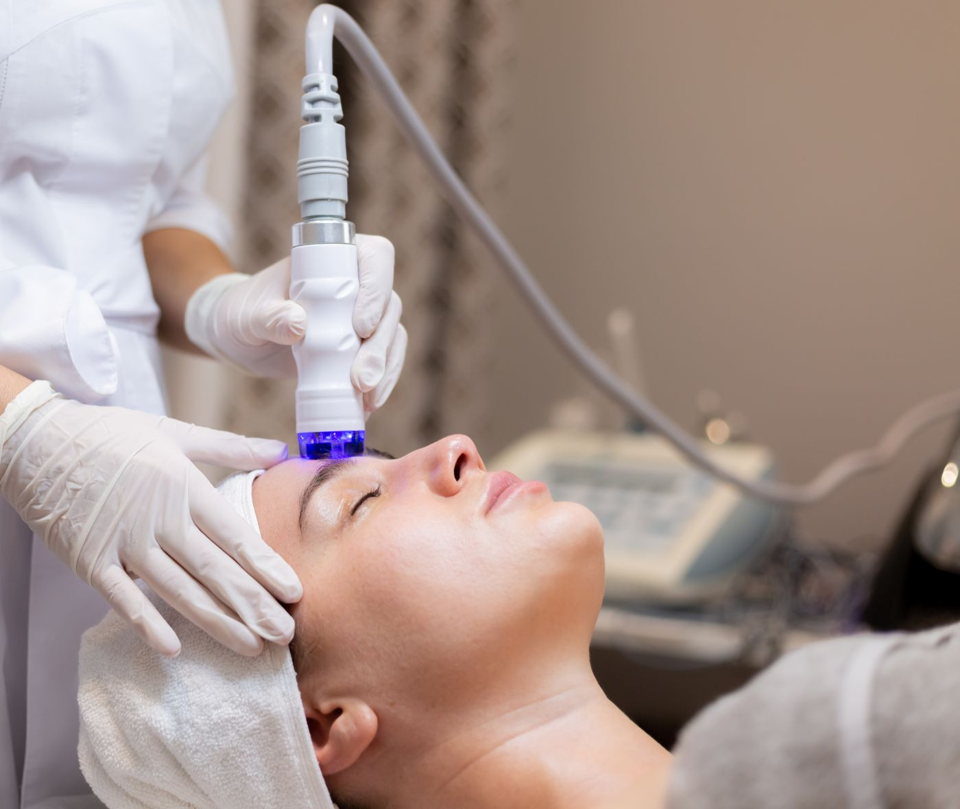 Woman receiving a facial treatment with a machine in a spa setting.