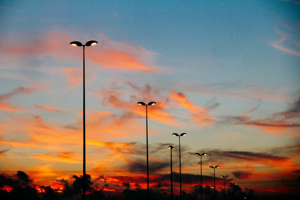 A row of street lights against a sunset sky