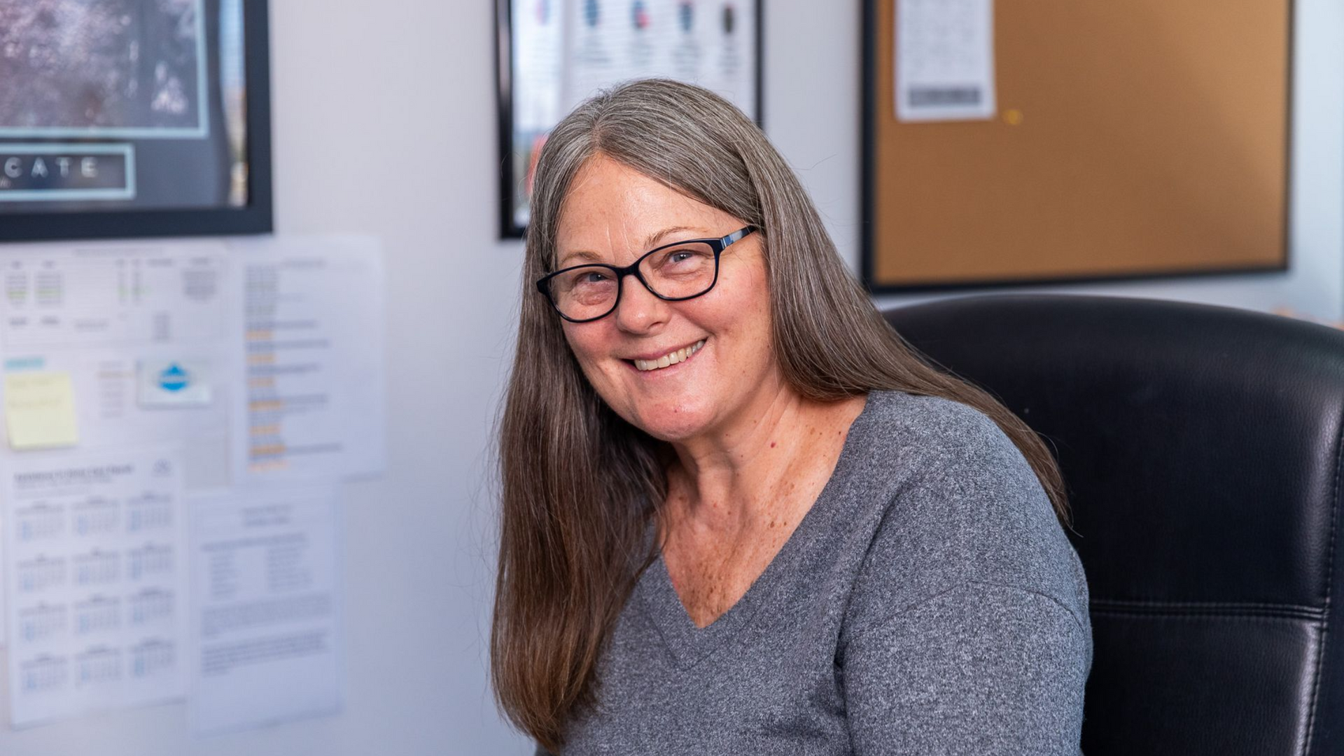 A woman is sitting at a desk talking on a phone.