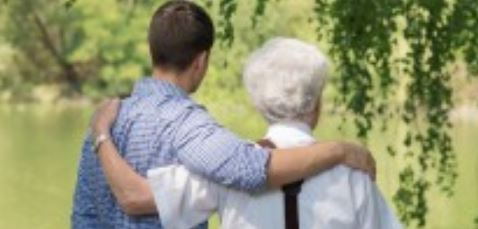 A young man is hugging an older man in a park.