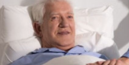 An elderly man is laying in a hospital bed.