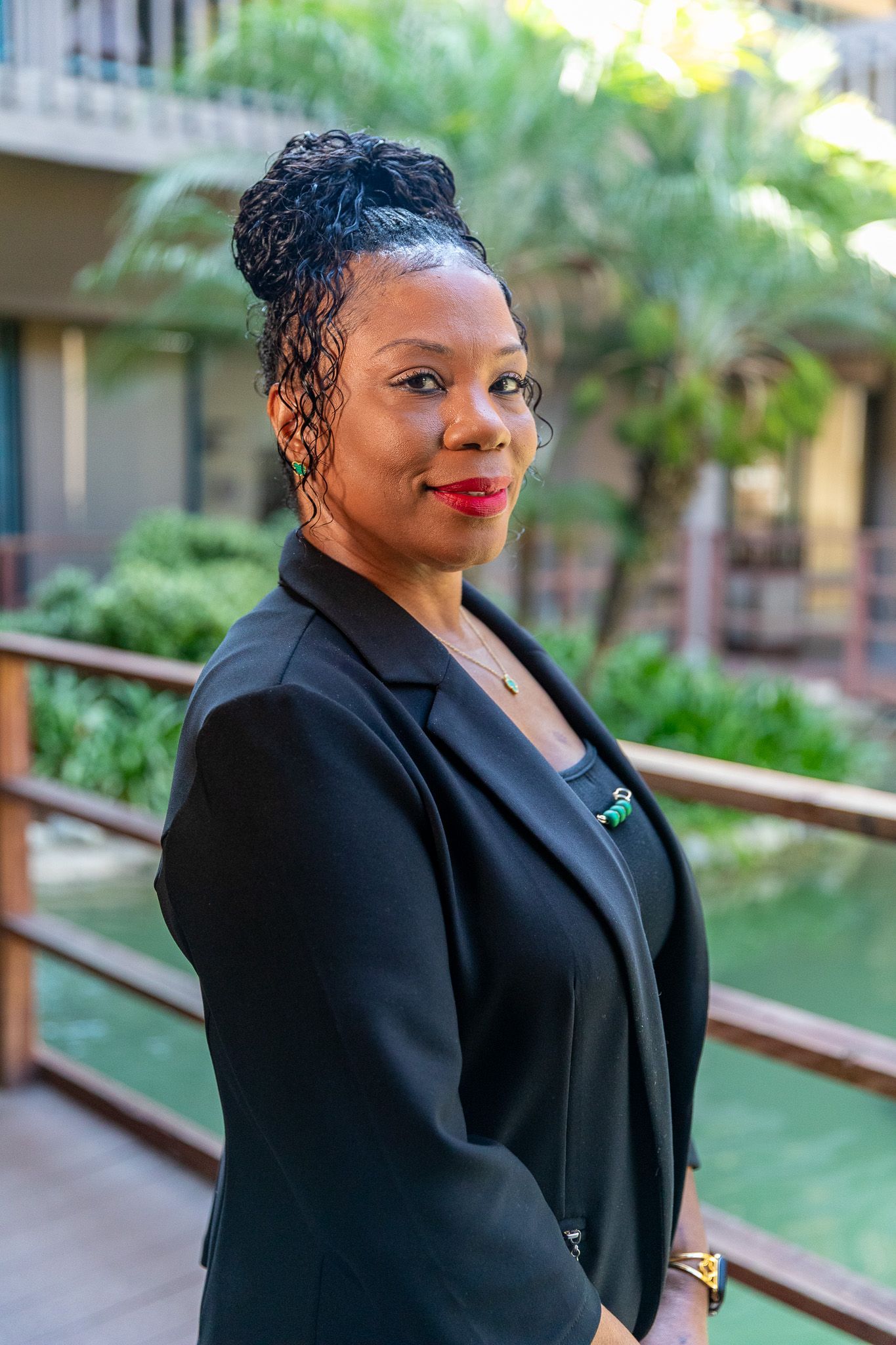 A woman in a floral shirt is standing on a wooden railing.