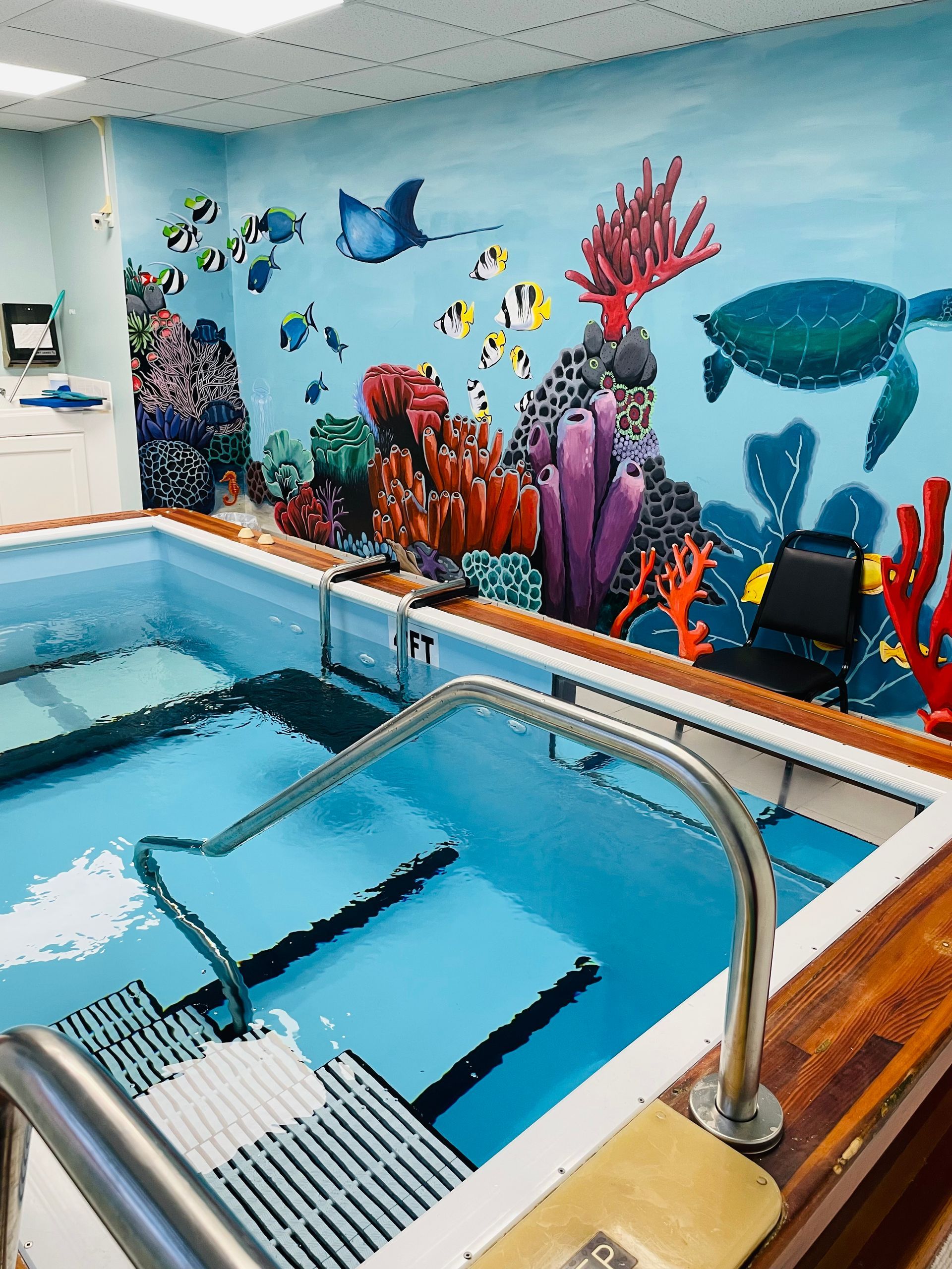 A swimming pool with a mural of a coral reef on the wall